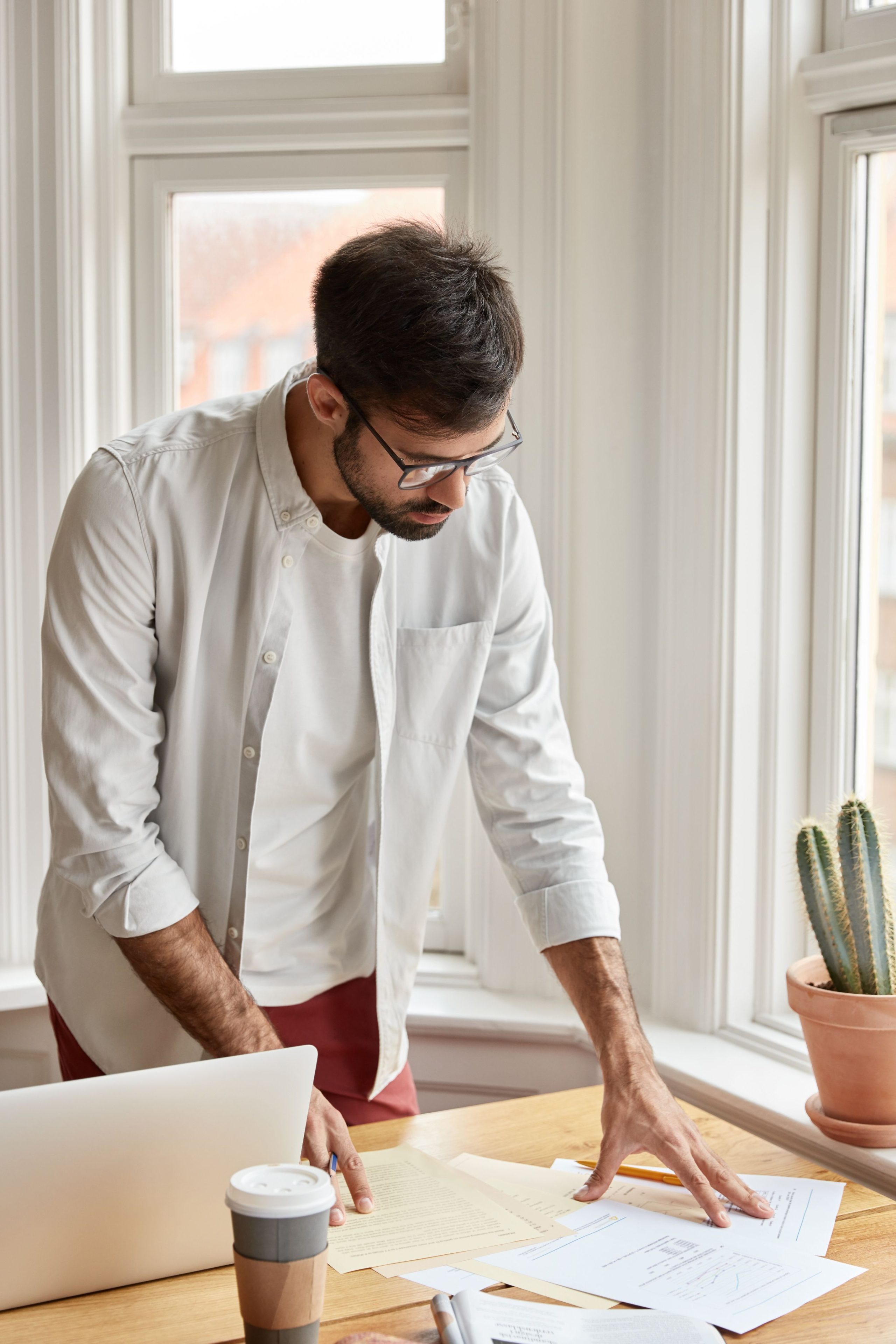 un homme en chemise blanche regarde des papiers sur un bureau.